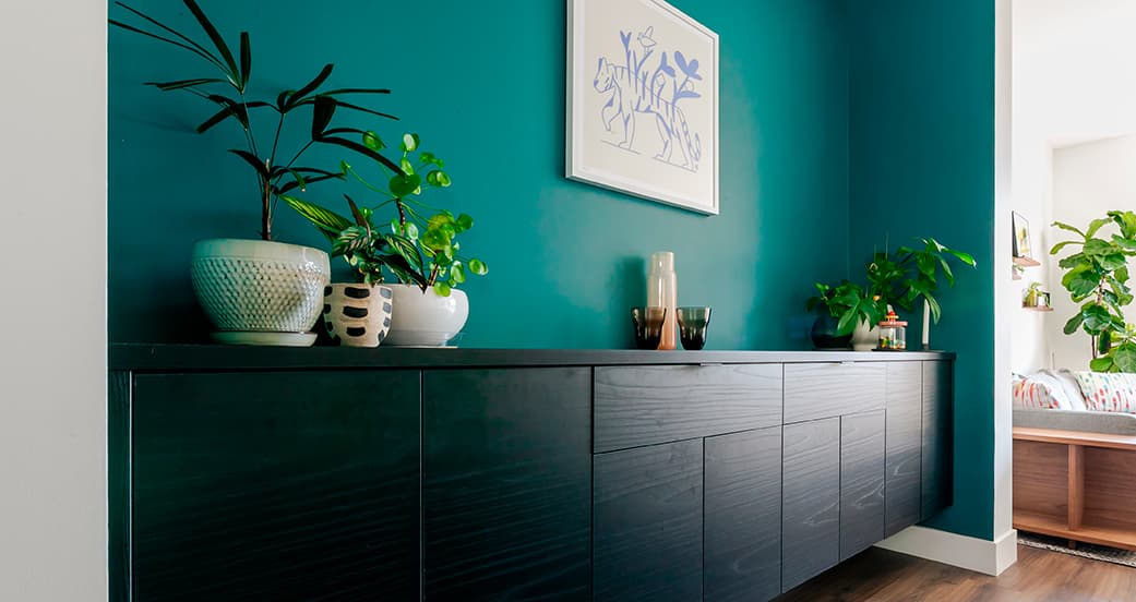 Streamlined home office with black work surface, open cubbies, and task lighting by California Closets.