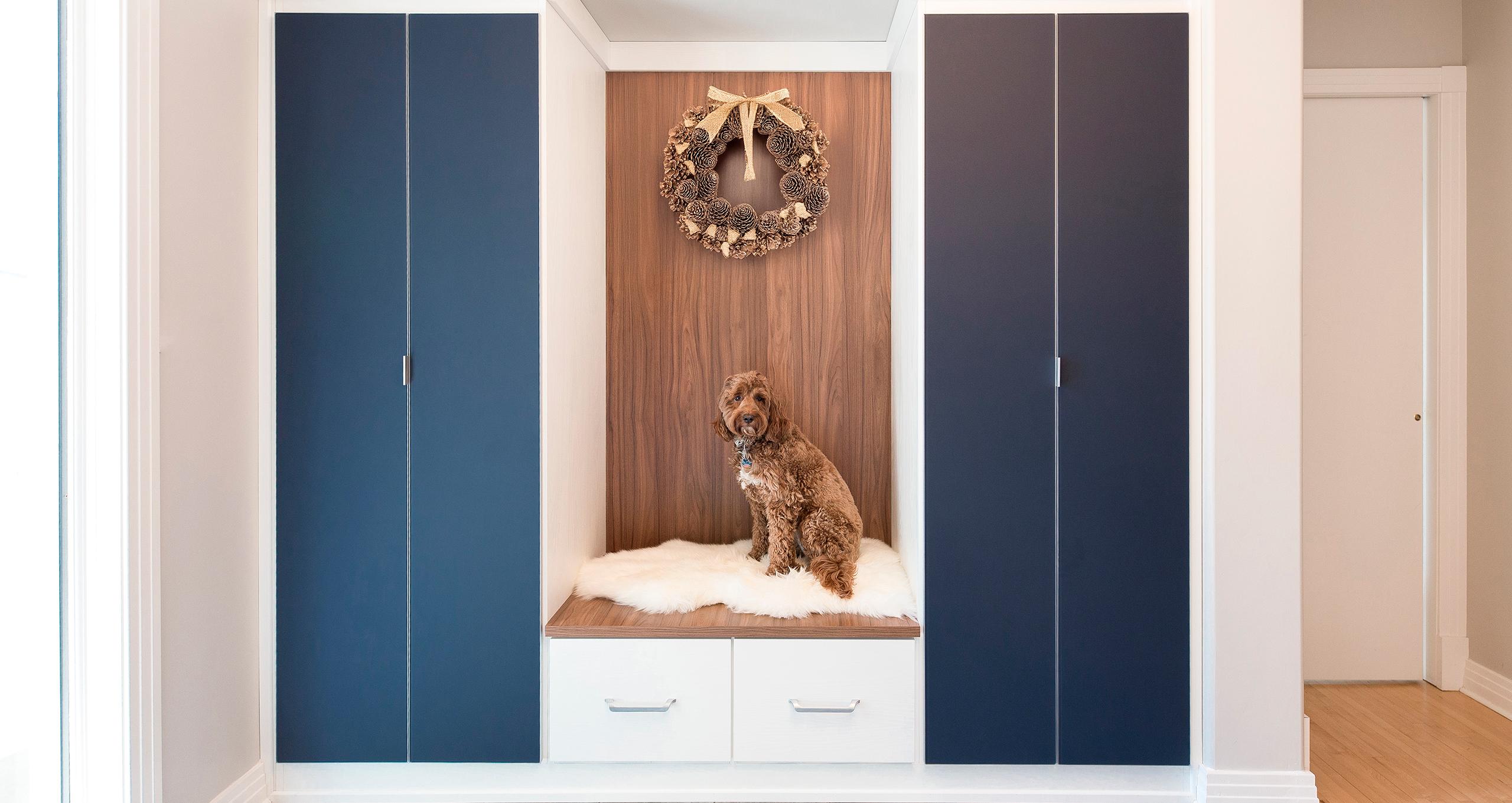 El recibidor luce diseño navideño con una corona colgada sobre banco y gabinetes personalizados de California Closets