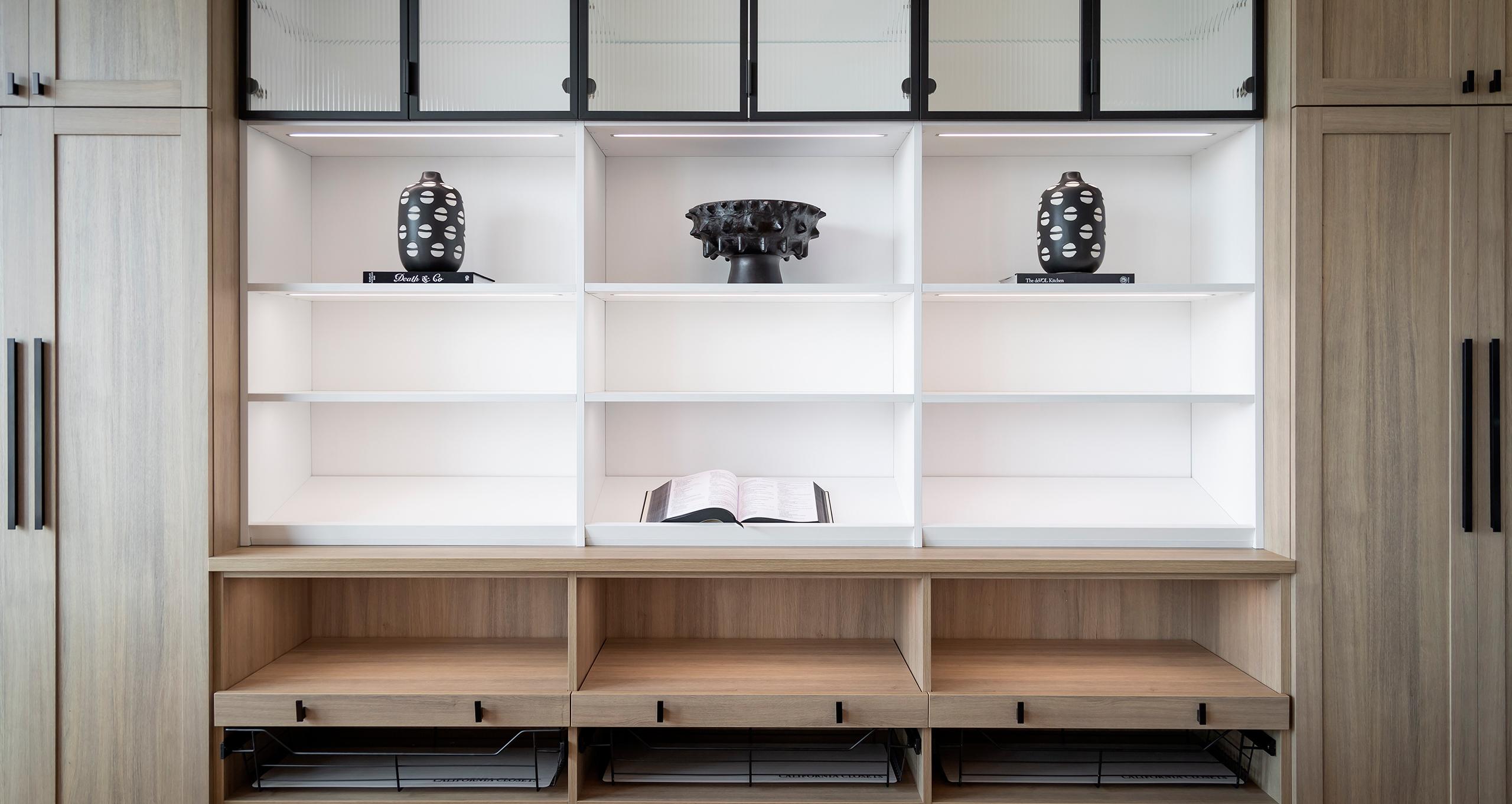 Sistema de repisas empotradas con iluminación personalizada para sala de estar de California Closets.