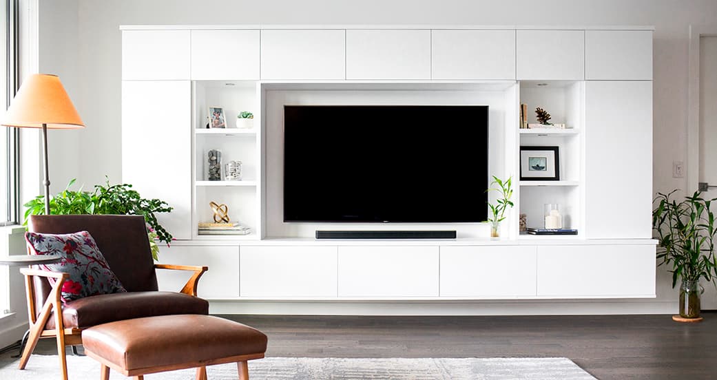 Custom white gloss finish entertainment center with floating shelving designed by California Closets
