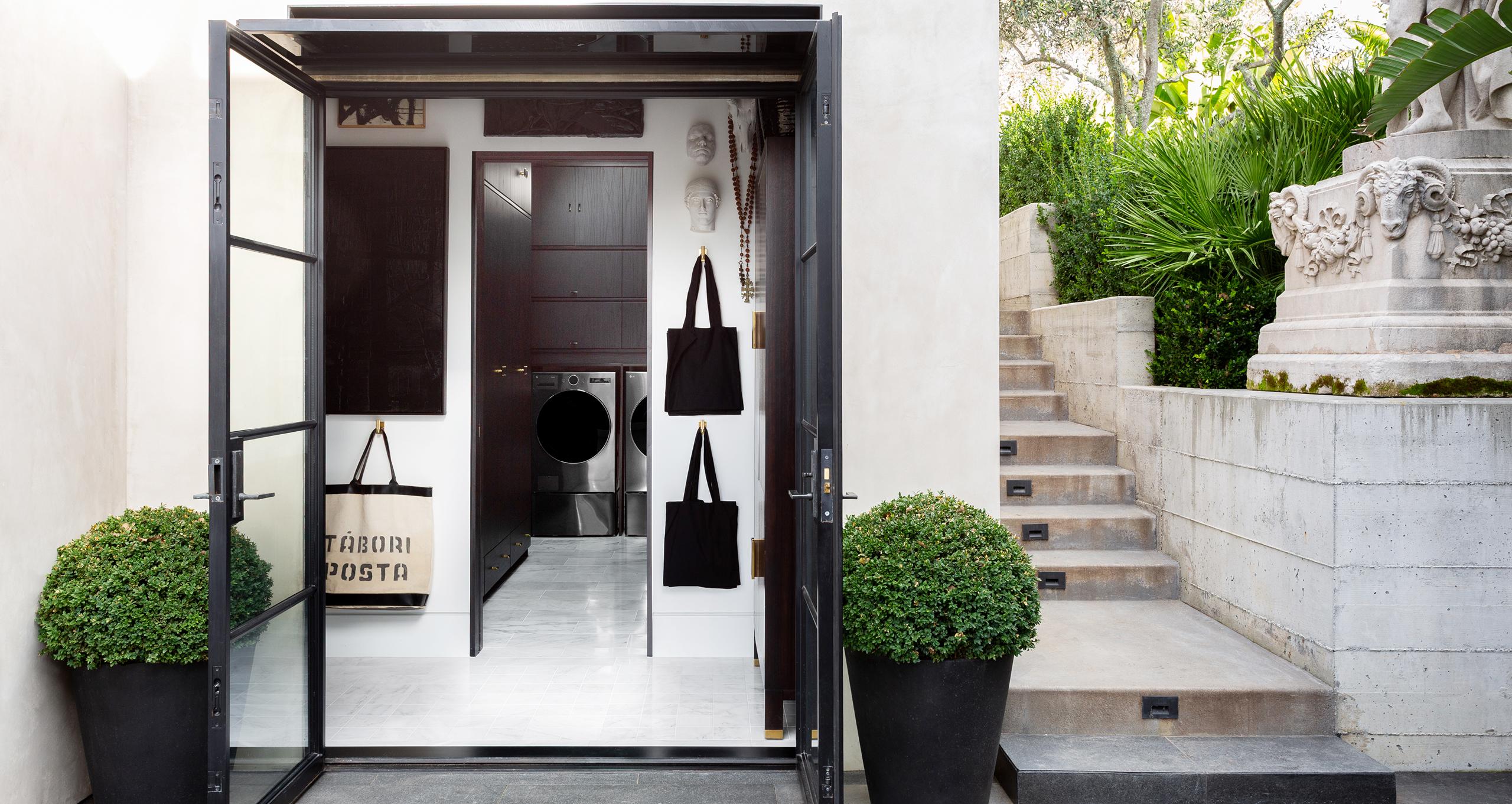 Hermosa lavandería diseñada con gabinetes oscuros, superficies de mármol y puertas francesas de California Closets