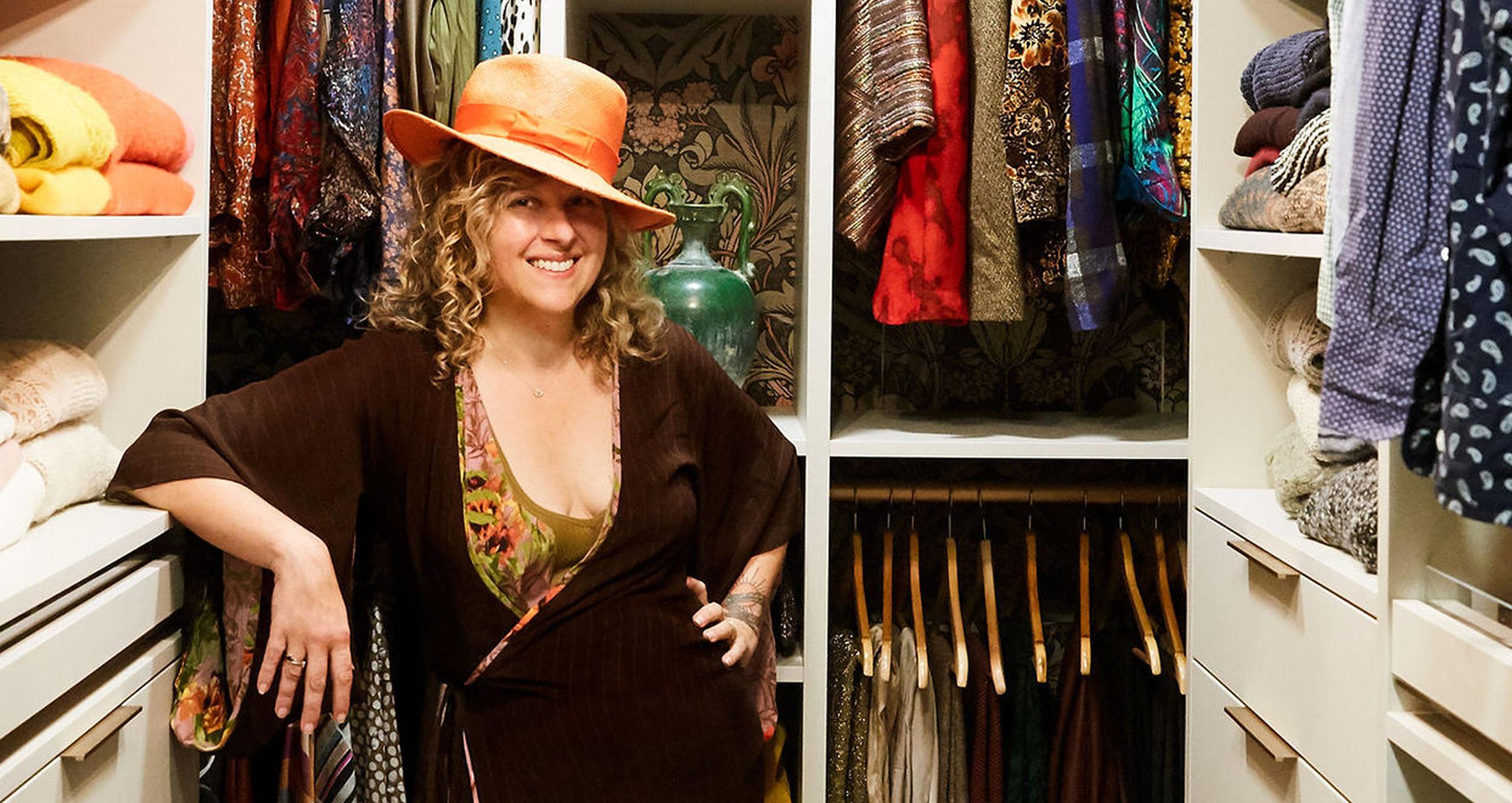 Olga Naiman standing in front of her walk-in closet customized with open shelving and drawers from California Closets