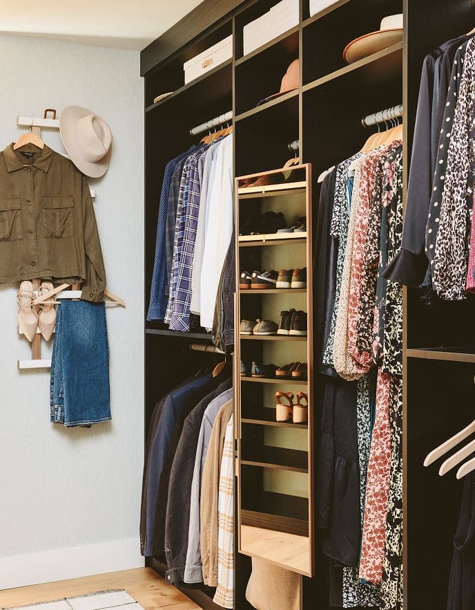 Clóset vestidor con carpintería oscura, almacenamiento colgante y organización personalizada por California Closets