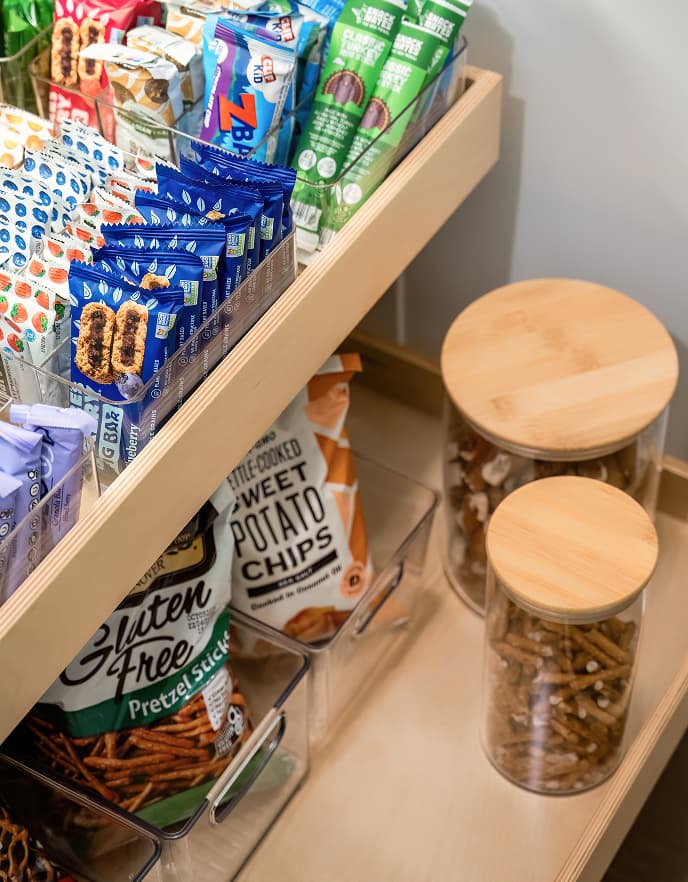 Cajones extraíbles de despensa con paquetes de snacks organizados y contenedores transparentes, California Closets