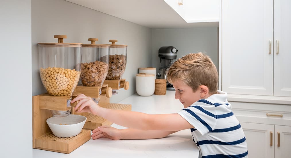 Dispensadores de cereal montados en la pared con contenedores transparentes y detalles de madera en una despensa personalizada, California Closets