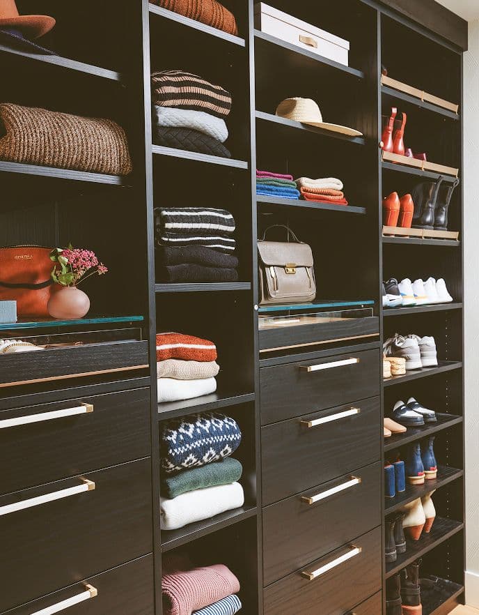 Walk-in closet with dark finish, shelves, drawers, and shoe storage by California Closets