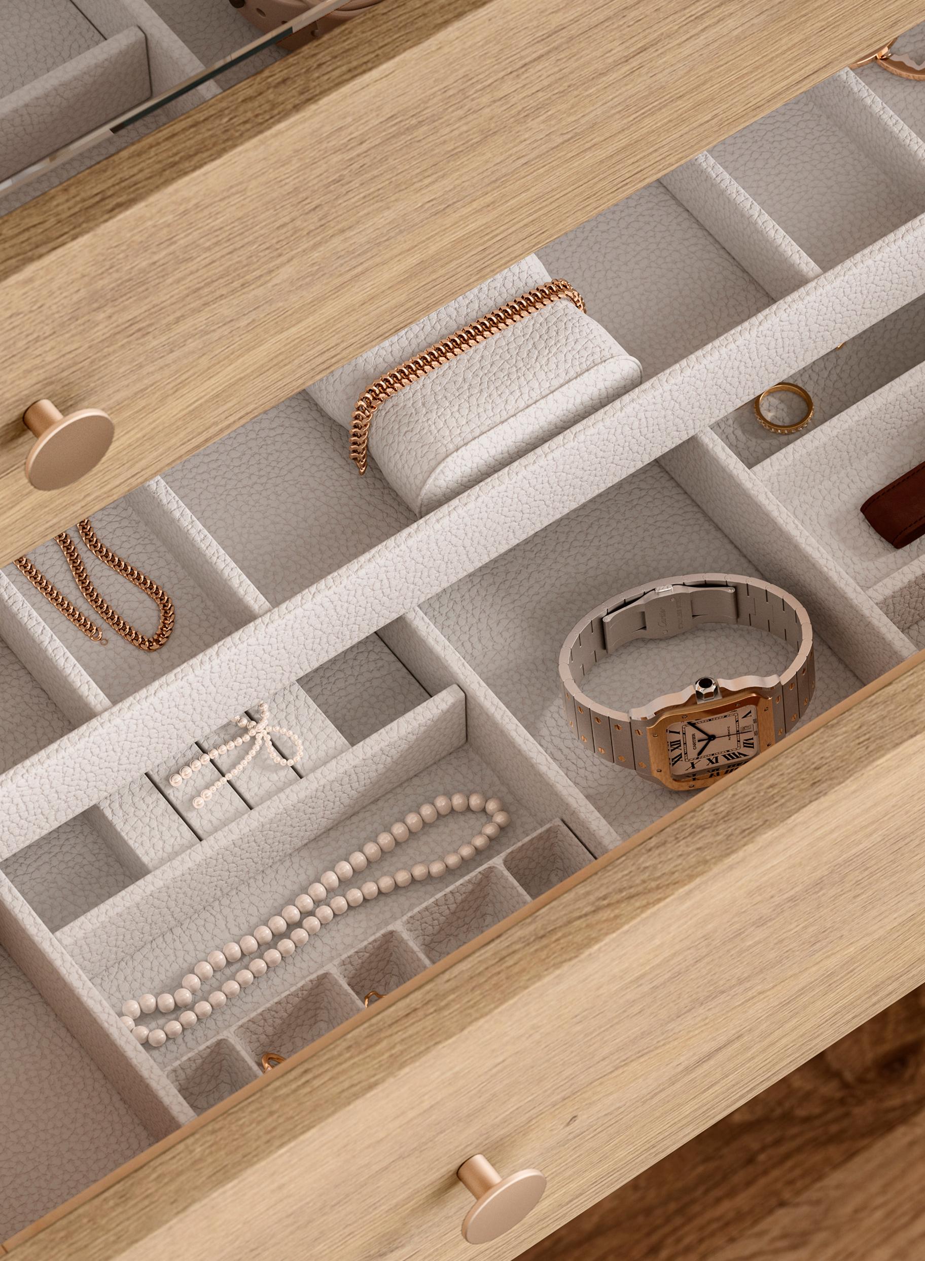 Jewelry drawer organizer with vegan leather insert, featuring sliding top tray and adjustable compartments for watches, rings, and accessories, designed for flexible, premium storage in a built-in closet system by California Closets.