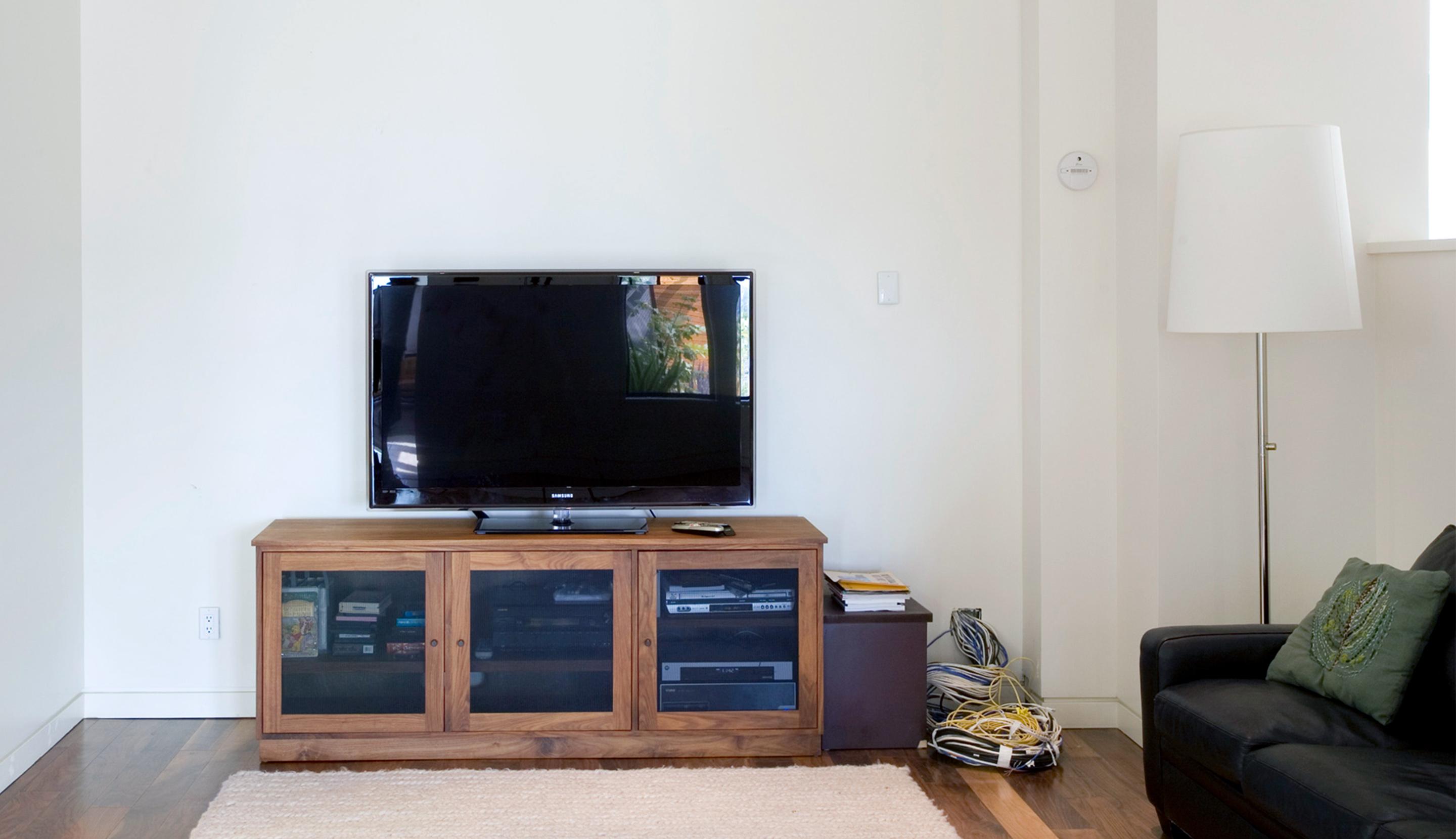 Outdated living room media console with limited storage and visible electronics by California Closets