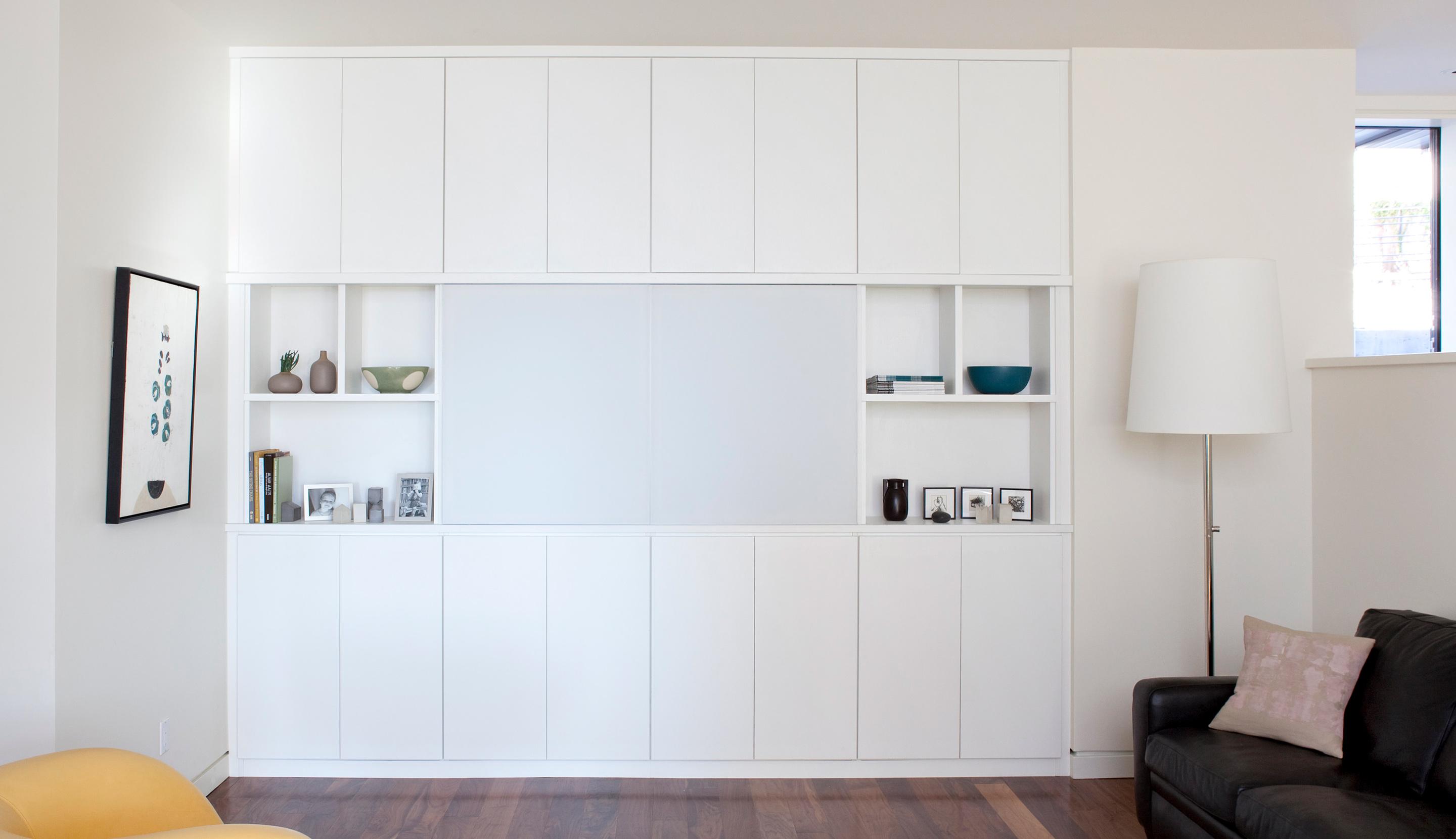 Sleek custom entertainment center with closed cabinets and open display shelving by California Closets