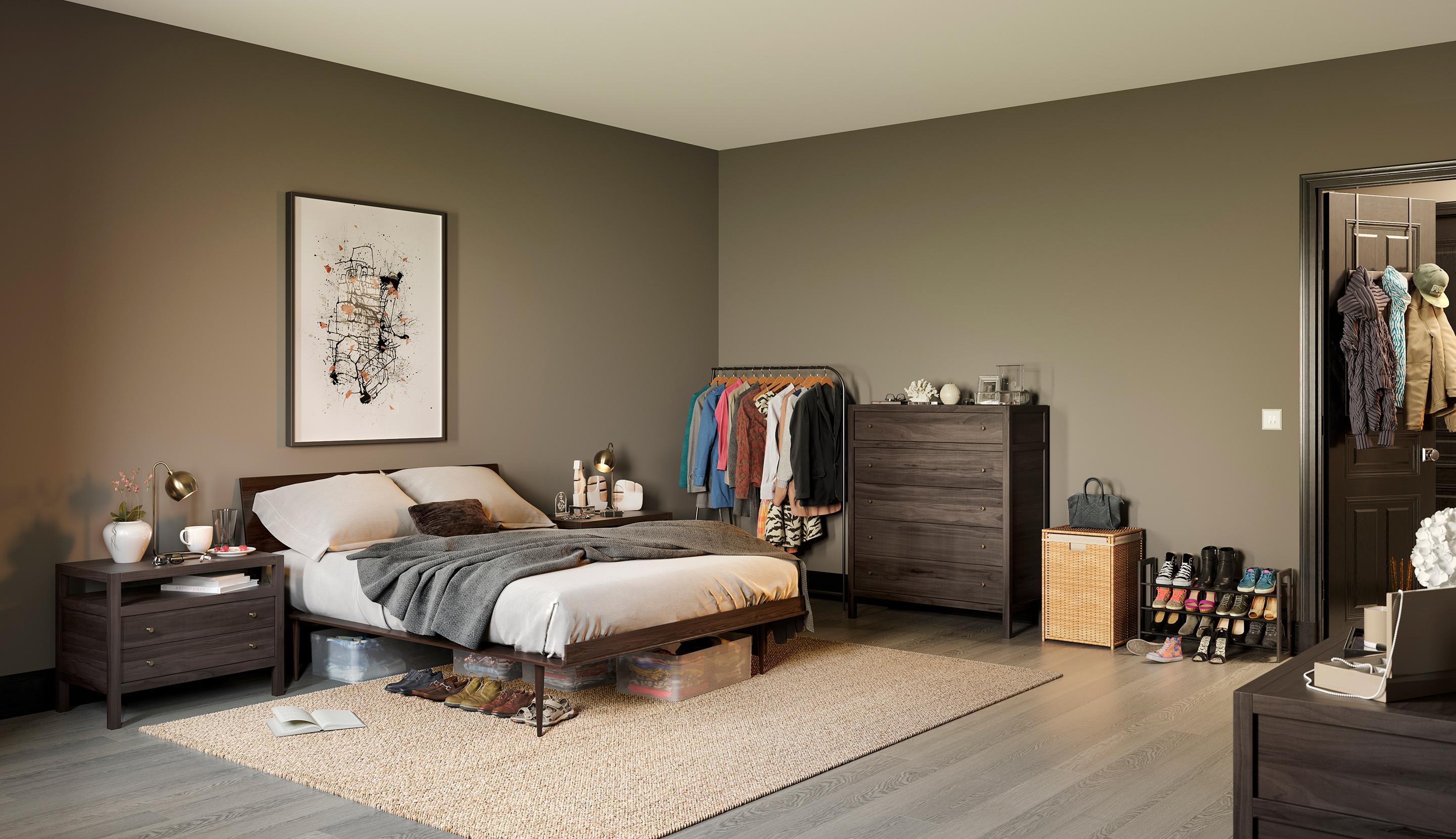 A modern, minimalist bedroom with taupe walls and grey wood flooring. The room features a dark wood bed frame with neutral bedding, a matching nightstand with a lamp, and a large piece of abstract art on the wall. A dark wood dresser, a black metal clothing rack, and a wicker laundry hamper are arranged along the far wall, with a shoe rack and an open doorway visible to the right.