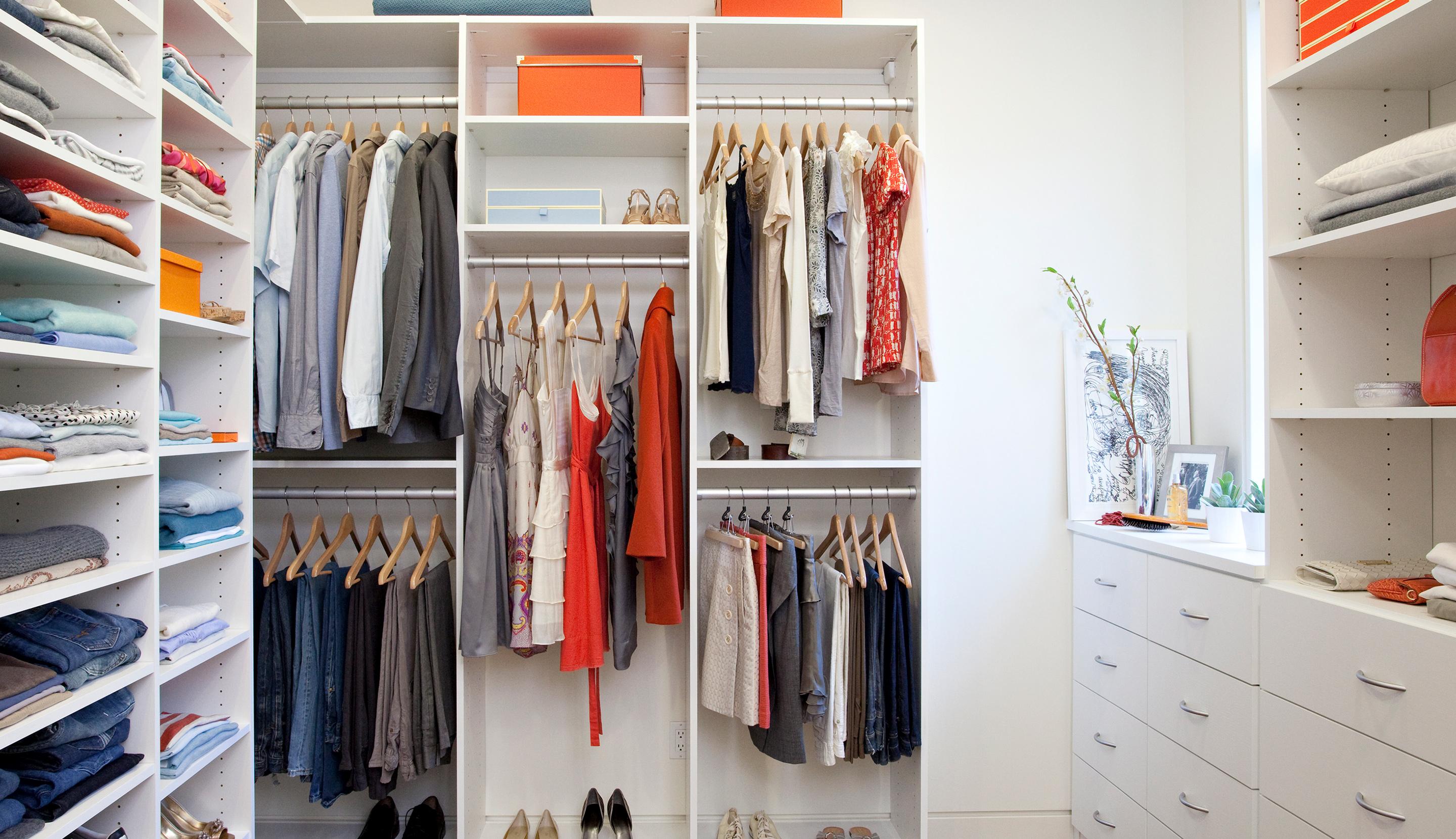 Walk-in closet featuring additional shelving, hanging rods, and organized clothing storage by California Closets