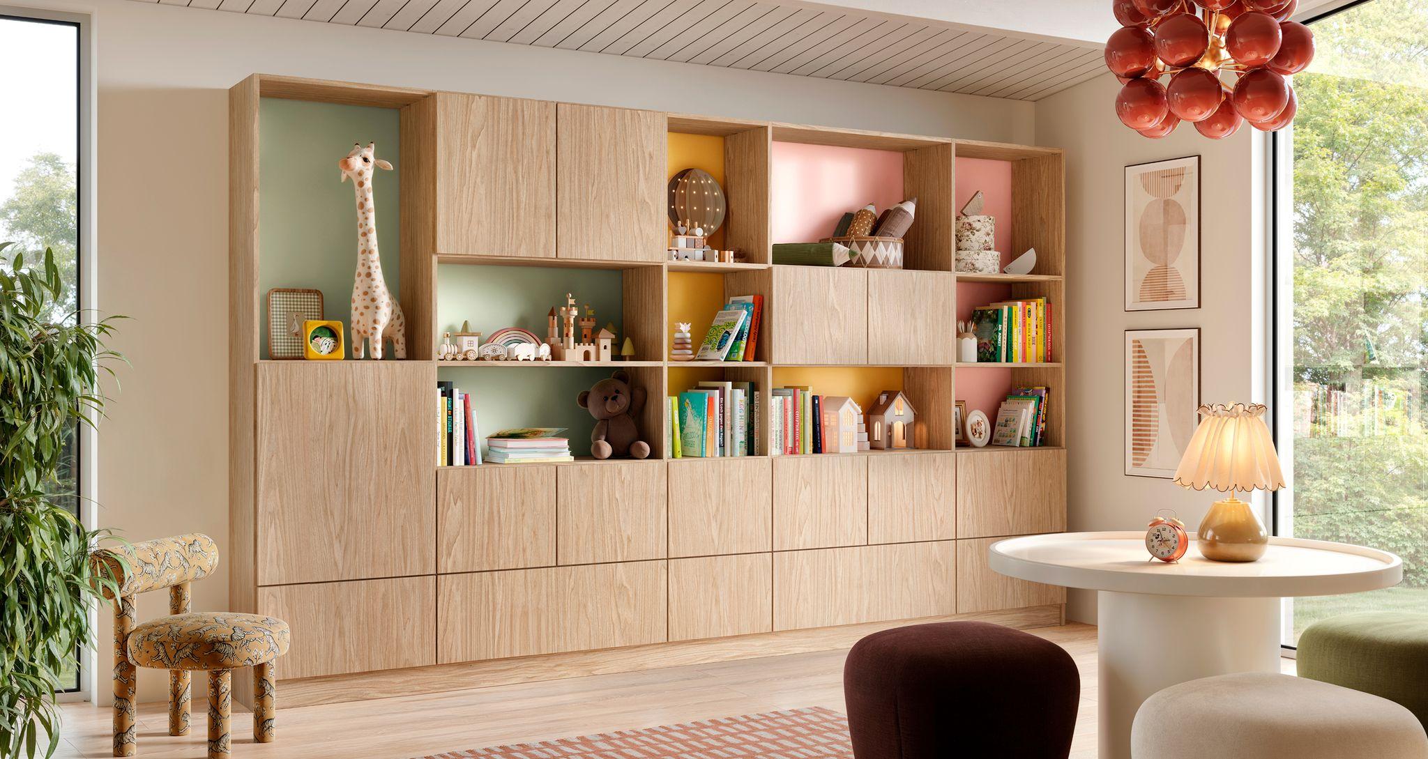 Modern light wood custom wall unit featuring colorful pastel back-painted glass panels in a child's playroom or creative space.