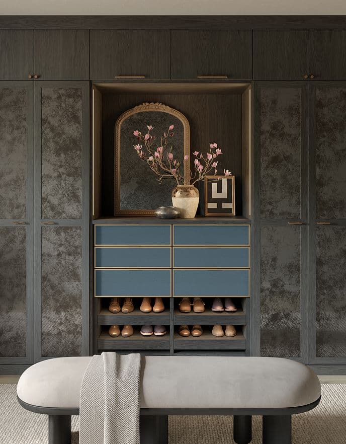 Elegant dark wood custom closet system with integrated lighting, textured door panels, and matte blue back-painted glass drawer fronts.