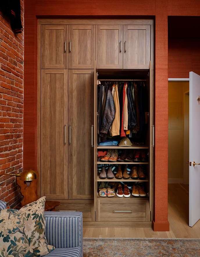 Custom walk-in wardrobe storage unit featuring adjustable shoe shelves and apparel clothing rods by California Closets.