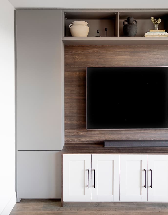 Unidad de pared para TV personalizada con gabinetes de almacenamiento integrados y estanterías abiertas de exhibición, diseñada por California Closets para una sala de estar contemporánea.