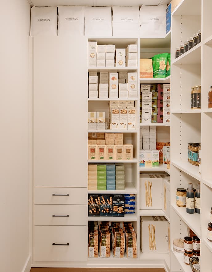 Estanterias de almacenamiento comercial personalizadas y diseno de despensa de inventario por California Closets para una boutique local de alimentos especiales.