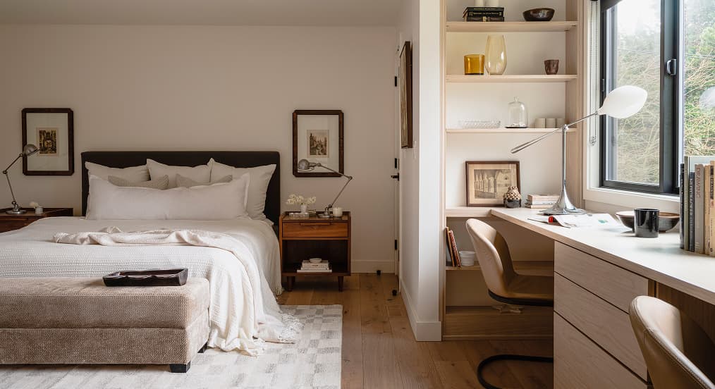 Diseño multifuncional de dormitorio y oficina en casa que presenta un escritorio empotrado personalizado y una unidad de estanterías junto a la ventana de California Closets.
