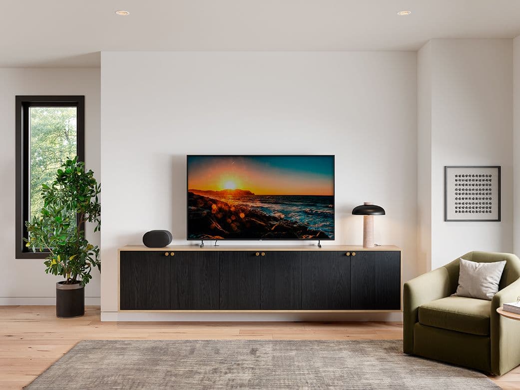 Custom floating media console with black doors and light wood trim under a TV by California Closets.