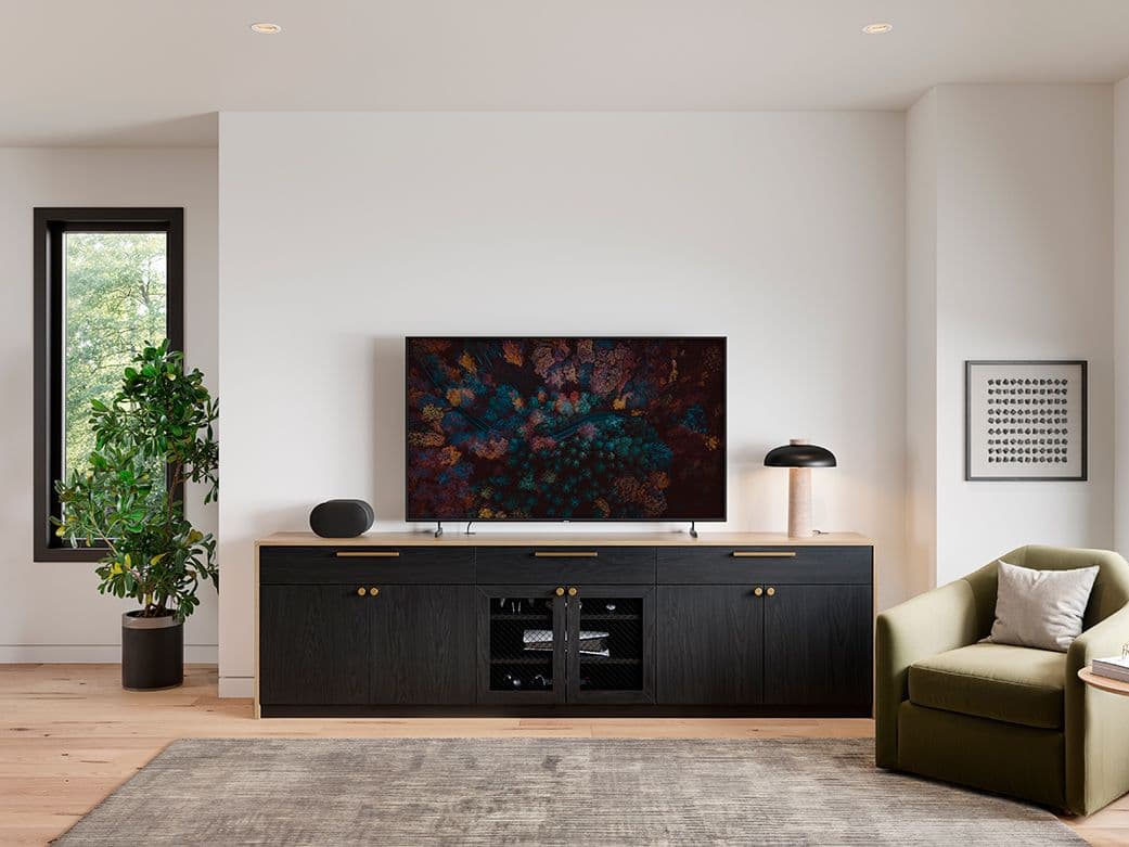 Custom black media console featuring top drawers and mesh center doors below a TV by California Closets.