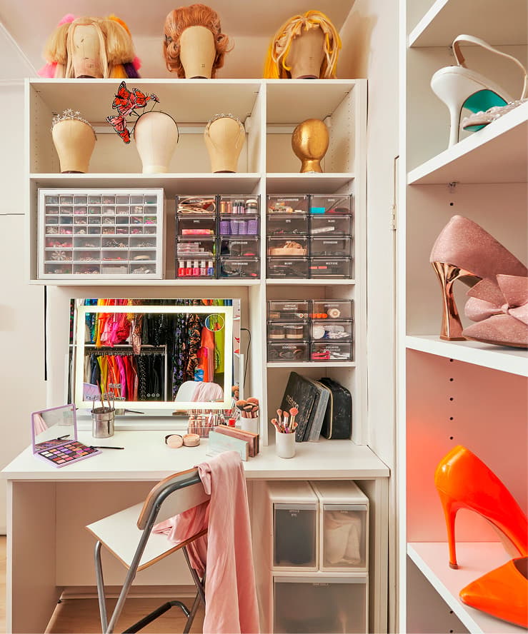 Custom white makeup vanity by California Closets featuring a lighted mirror, storage drawers, and wig display shelves.
