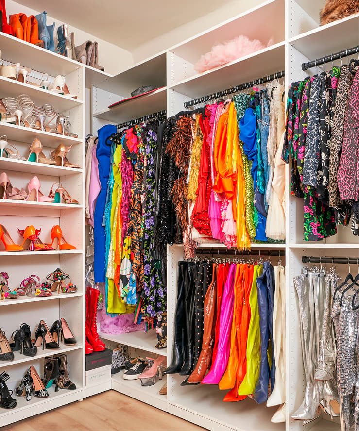 Sistema de clóset vestidor blanco de California Closets lleno de vestidos coloridos, zapatos y botas colgantes