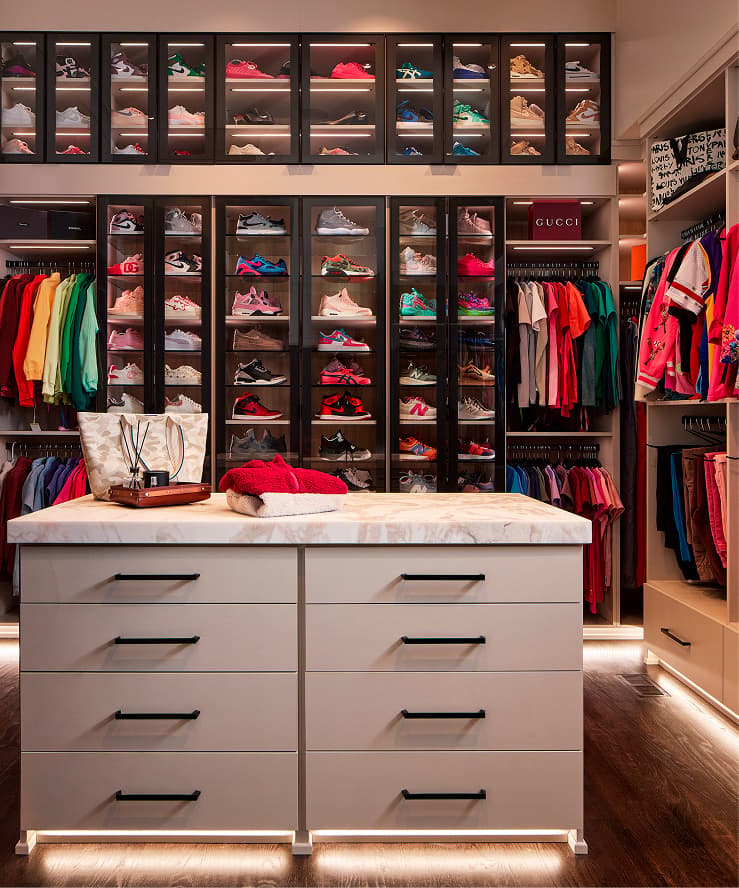Custom dressing room island and illuminated sneaker display wall designed for LadySpineDoc by California Closets