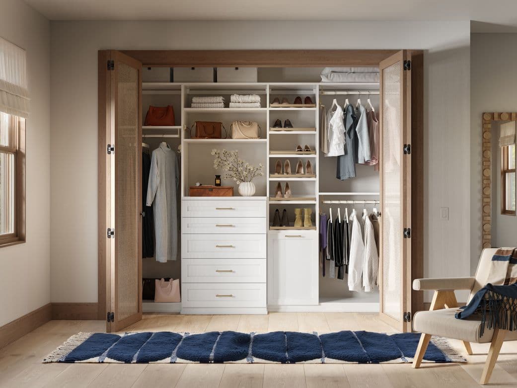 Reach in closet designed to floor storage with drawers and hamper in light finish by California Closets