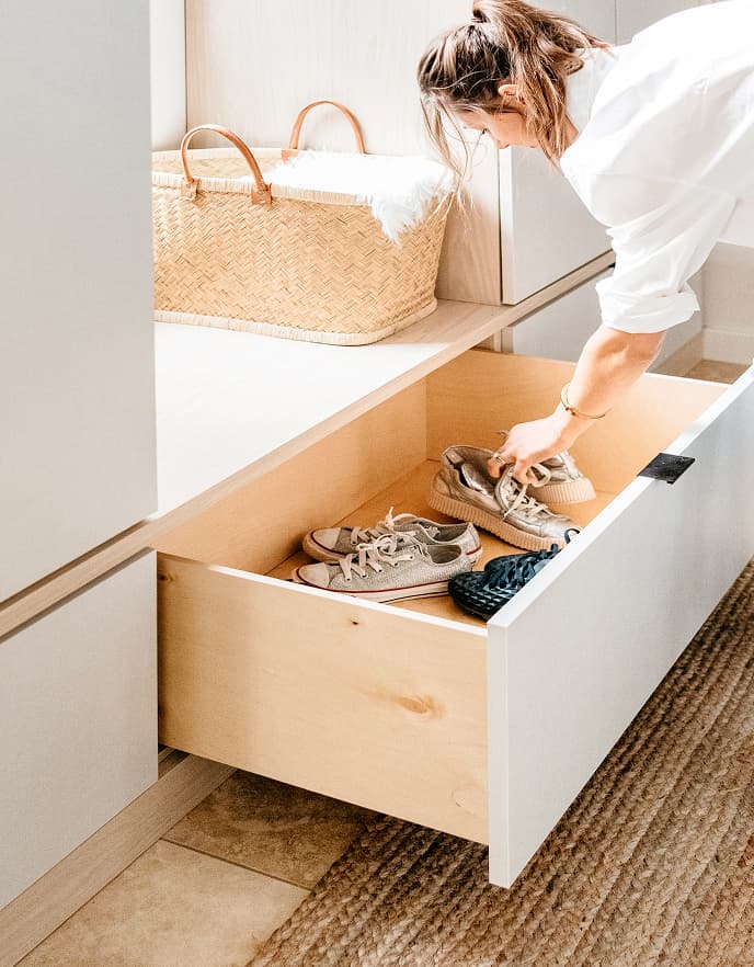 Cajón integrado en la entrada que ofrece
almacenamiento oculto para zapatos de
California Closets.