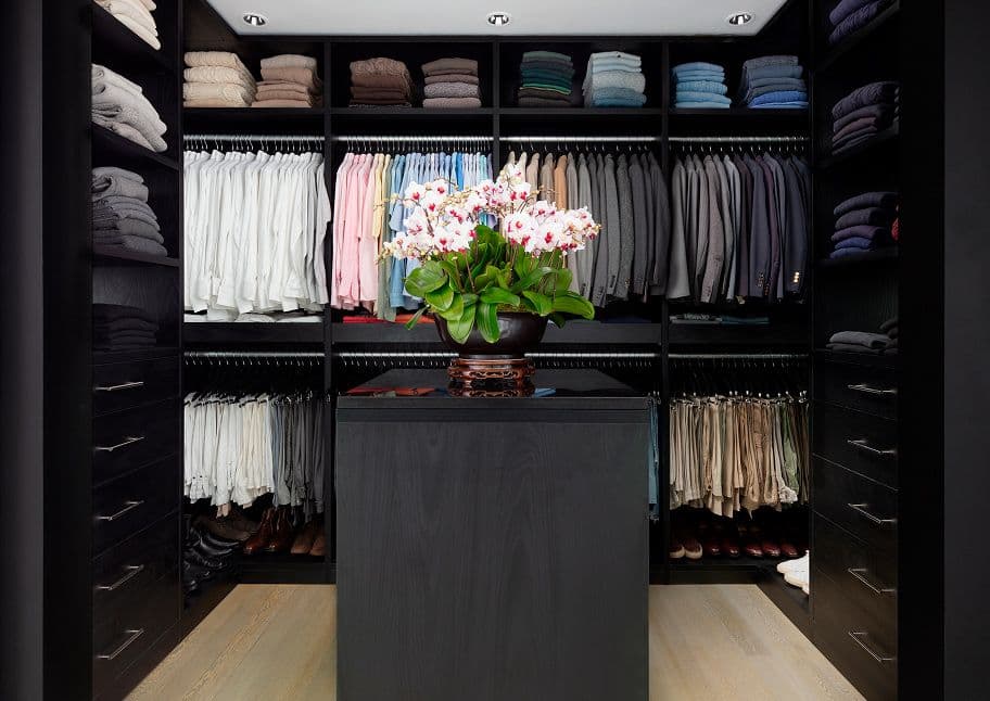 Custom walk in closet with storage island and shelving in navy finish by California Closets