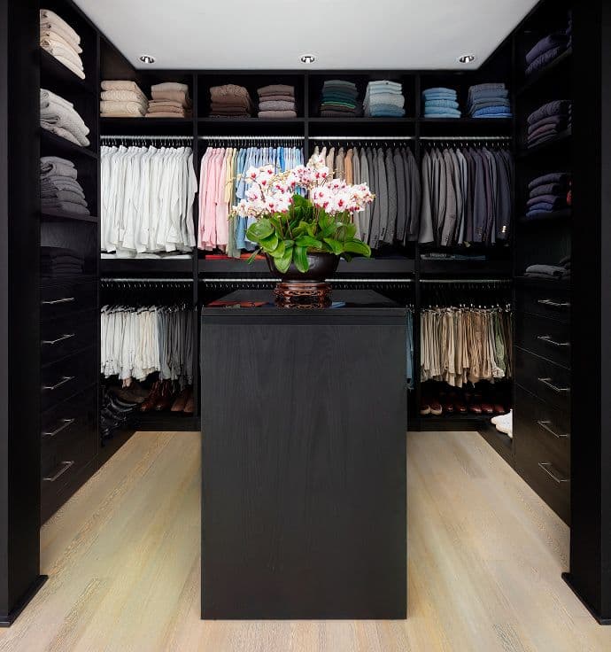 Custom walk in closet in navy finish with center island storage drawers by California Closets