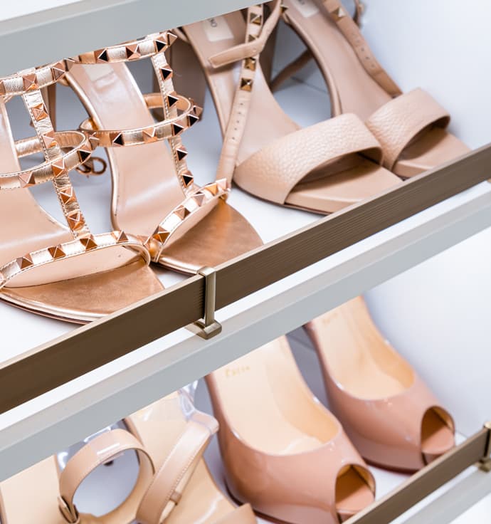 Custom shoe racks in a custom closet with toe rails and LED lighting designed by California Closets