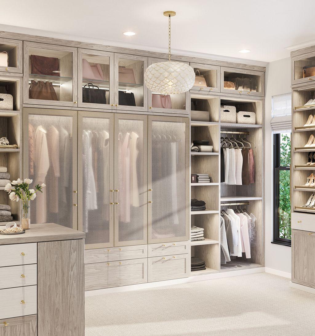 Vestidor con acabado en madera clara, puertas de armario transparentes y estanterías empotradas de California Closets