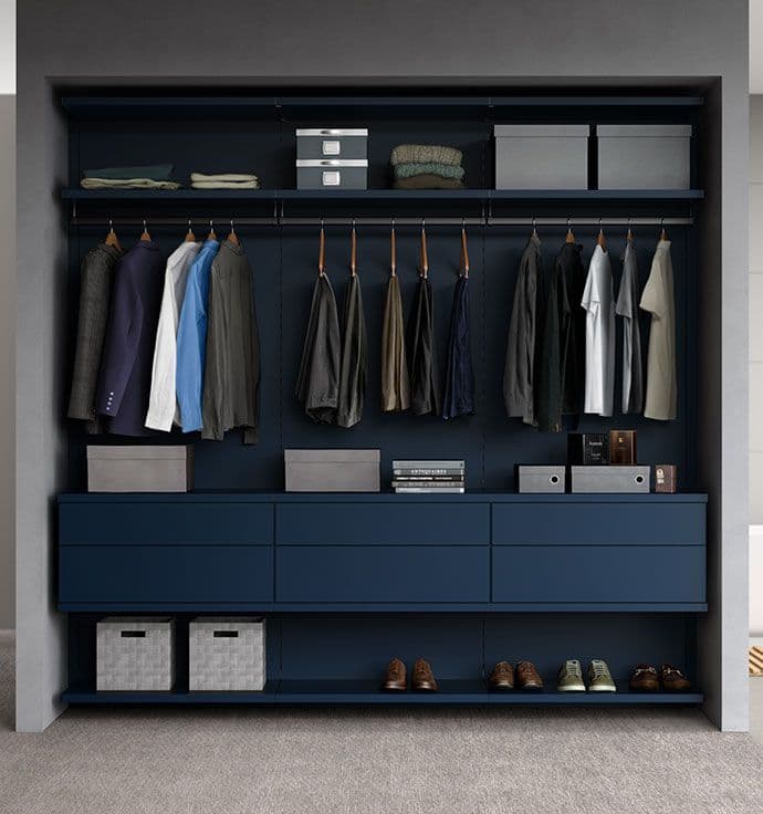 Custom reach in closet in dark blue finish with overhead storage shelf, shoe storage and floating drawers by California Closets