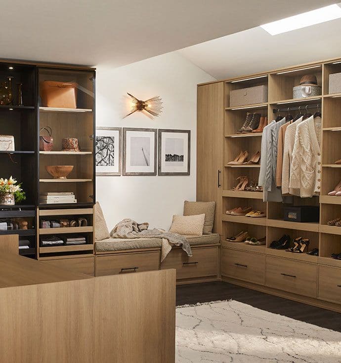 Customized walk in closet with natural and ribbon led lighting, island, bench seat in natural finish by California Closets