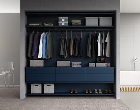 Diseño de armario empotrado con almacenamiento expuesto, sistema de zapatos y barra para colgar en un acabado azul marino de California Closets